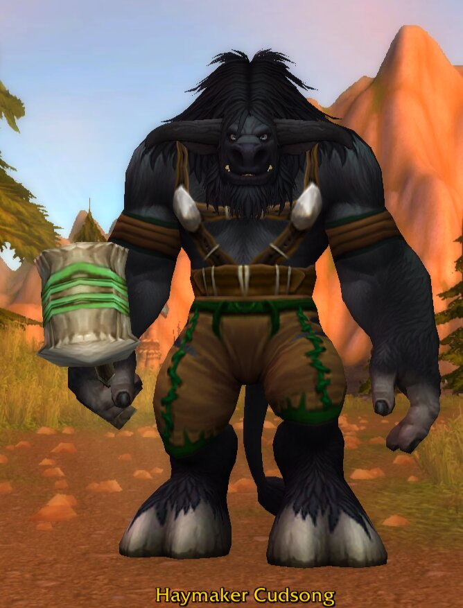 Haymaker Cudsong, a black-furred tauren with a long black mane, a full black beard and dark horns curving forward, wearing a leather harness hung with two white tusks and brown trousers with green stitching, holding a big wooden mallet bound with green bands, standing on a dirt road in Mulgore with orange mesas behind him